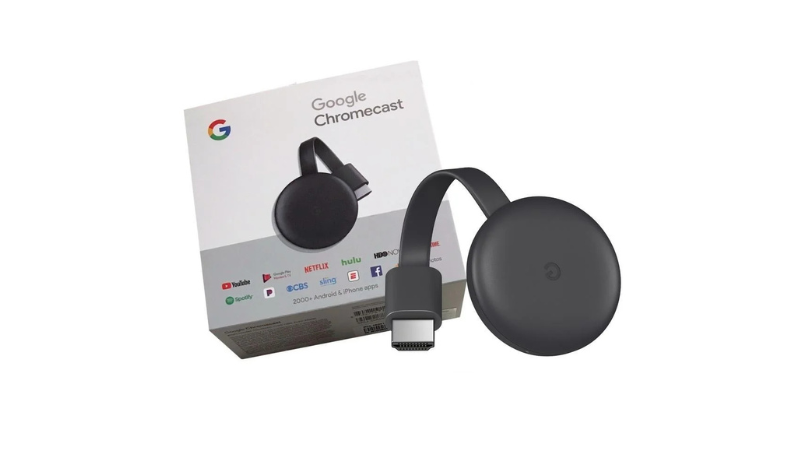 Dispositivo Google Chromecast de terceira geração, na cor preta, com seu cabo HDMI flexível e a caixa branca do produto ao fundo, mostrando os logotipos de aplicativos de streaming como Netflix e YouTube.