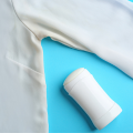 Axila de uma camisa branca com mancha amarelada de suor e desodorante, ao lado de um desodorante branco em bastão sobre fundo azul.
