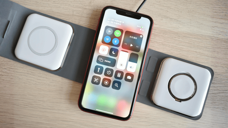 Carregador sem fio com base para celular sobre mesa de home office organizada.