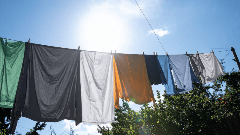 Roupas penduradas em varal ao ar livre secando ao sol, mostrando secar roupas de forma natural e econômica.